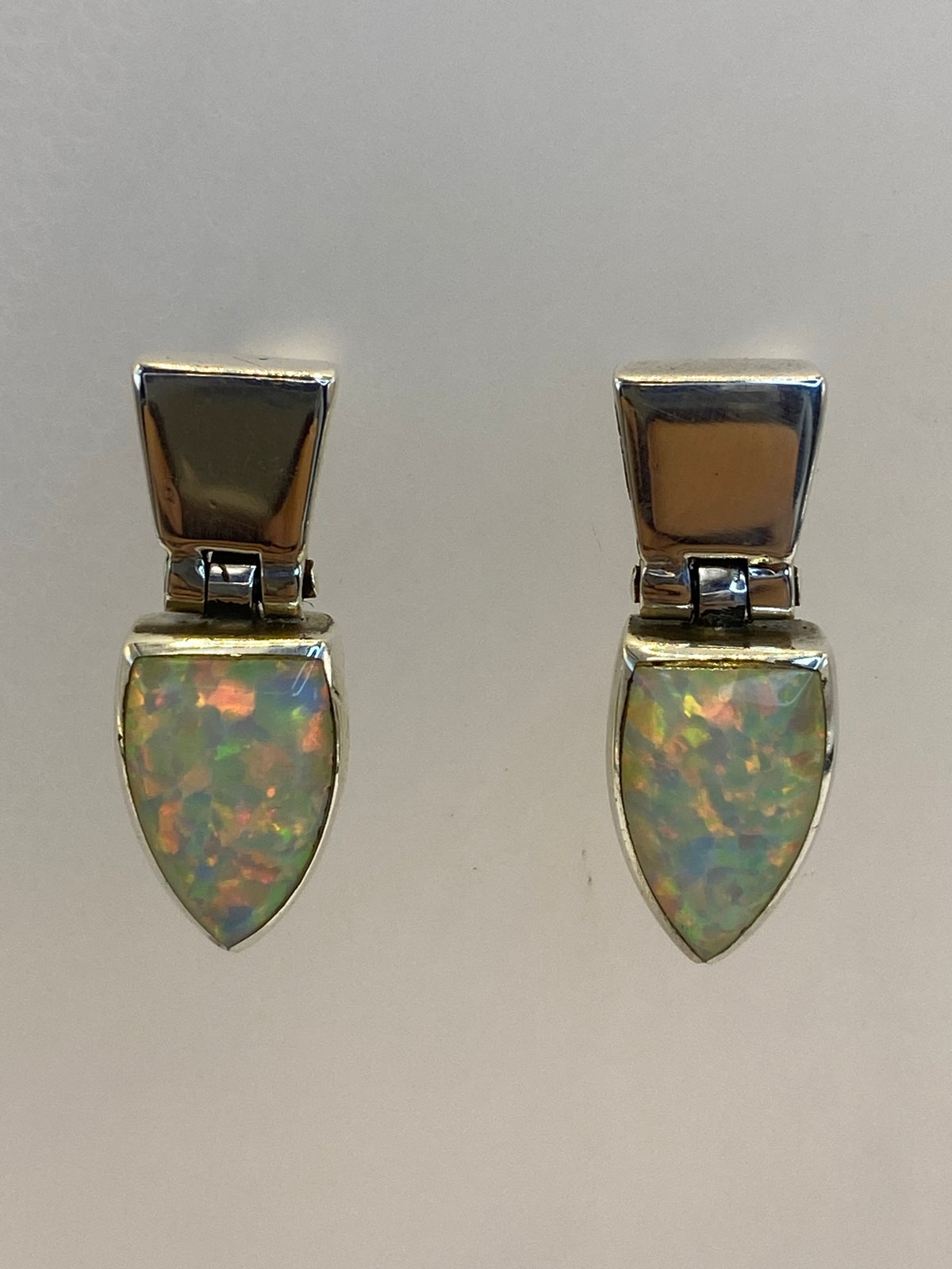 Par de aretes de plata con ópalo de fuego multicolor, mostrando reflejos rojos, naranjas y verdes