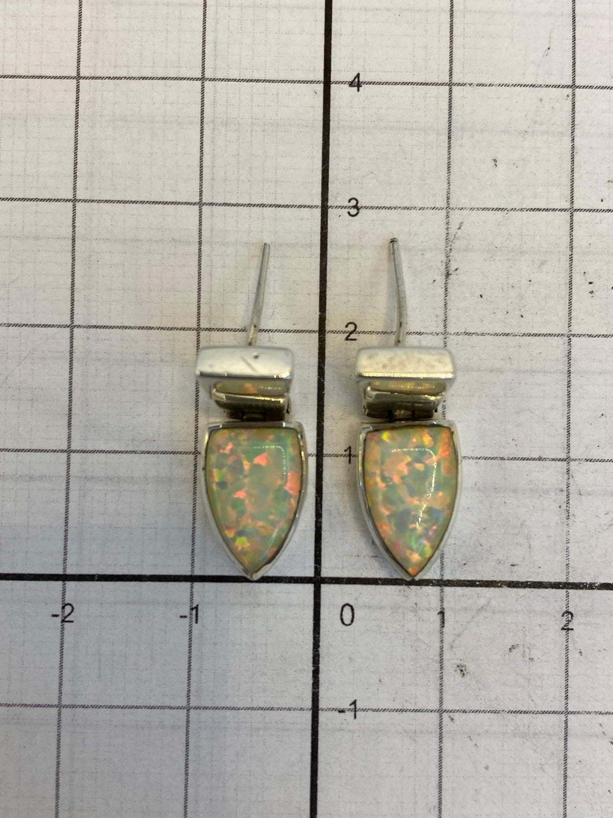 Medida del largo de los aretes (2.6 cm) contra regla, mostrando proporciones