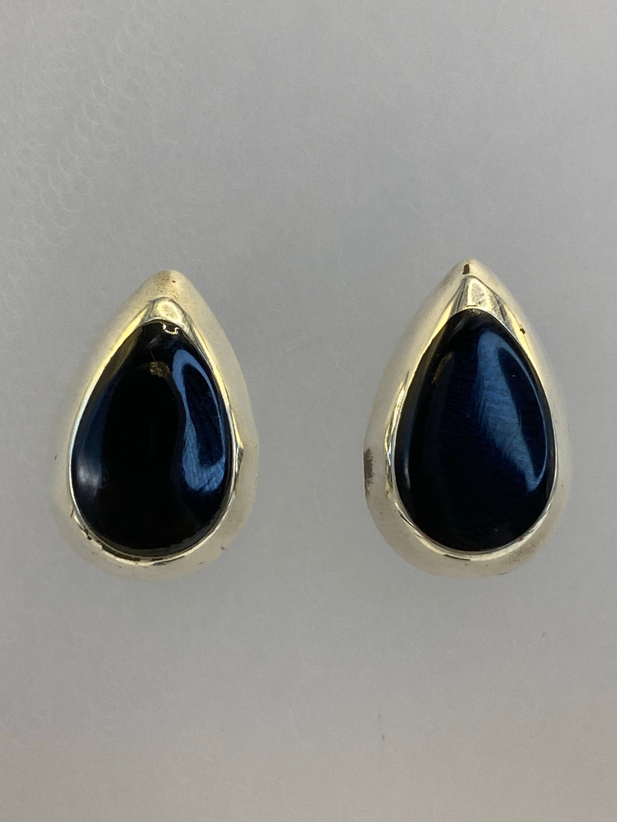Par de aretes de plata con onix negro pulido, vista frontal mostrando el tamaño compacto