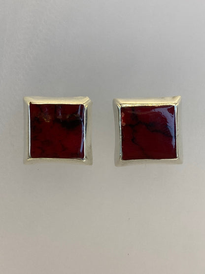 Aretes de plata con piedra multicolor de Taxco en la mano