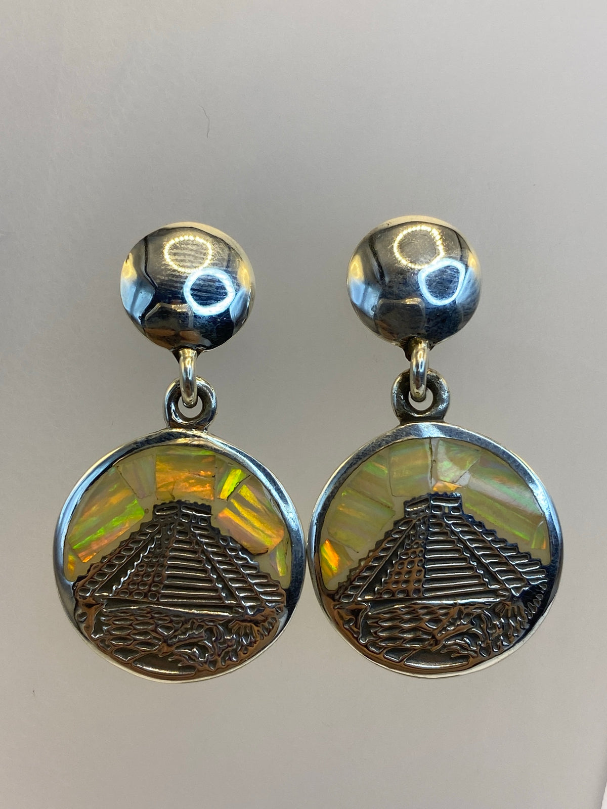 Par de aretes de plata 950 con ópalo de fuego multicolor en diseño de pirámide prehispánica, vistos de frente