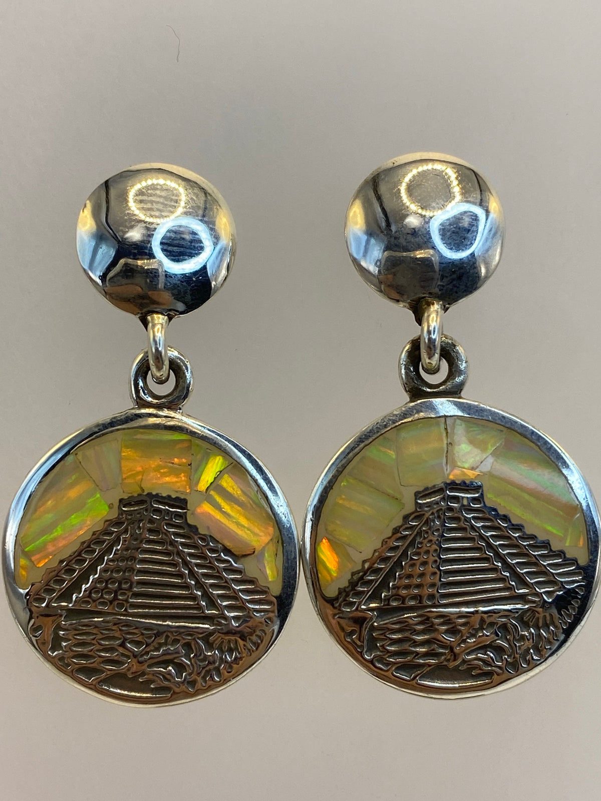 Aretes puestos en una mujer, brillando con los tonos multicolores del ópalo