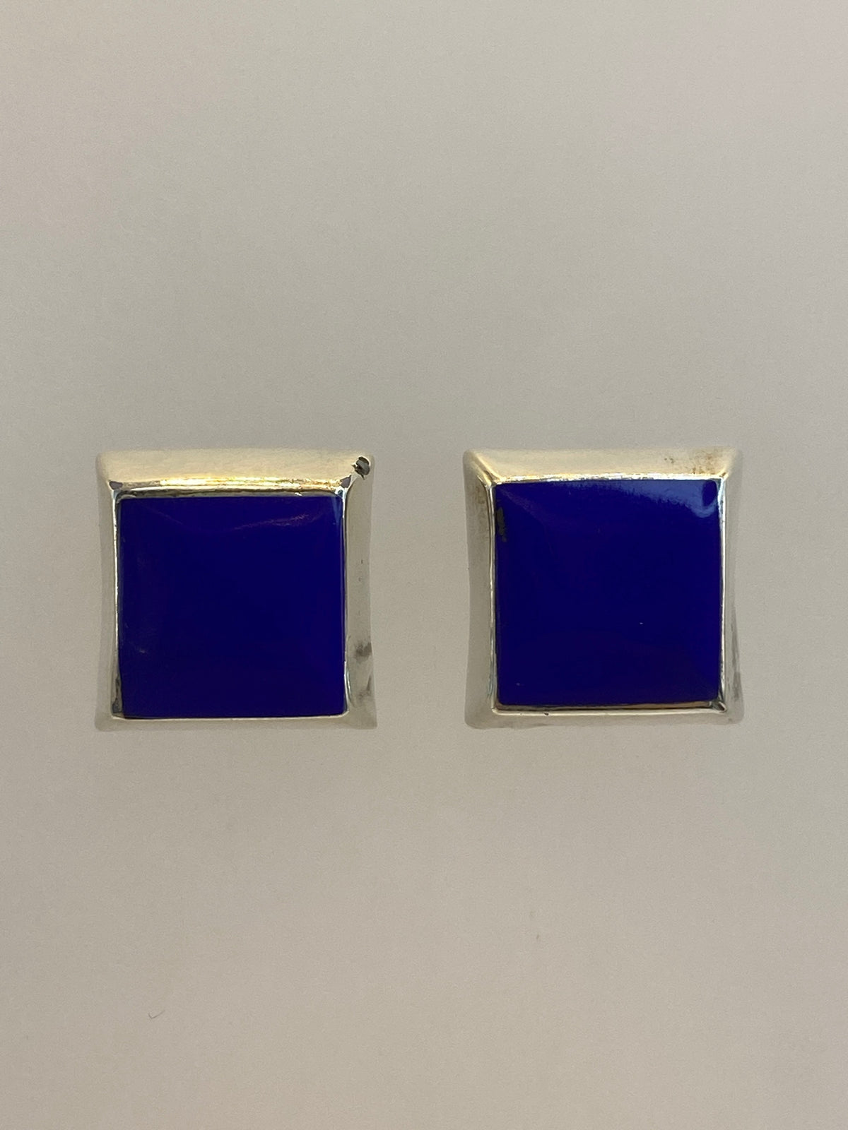 Detalle frontal de un arete cuadrado mostrando la piedra azul y el pulido de la plata 925