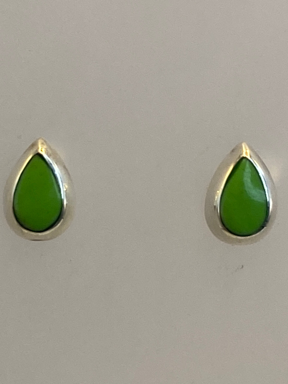 Aretes de plata verde olivo vistos de frente sobre fondo blanco