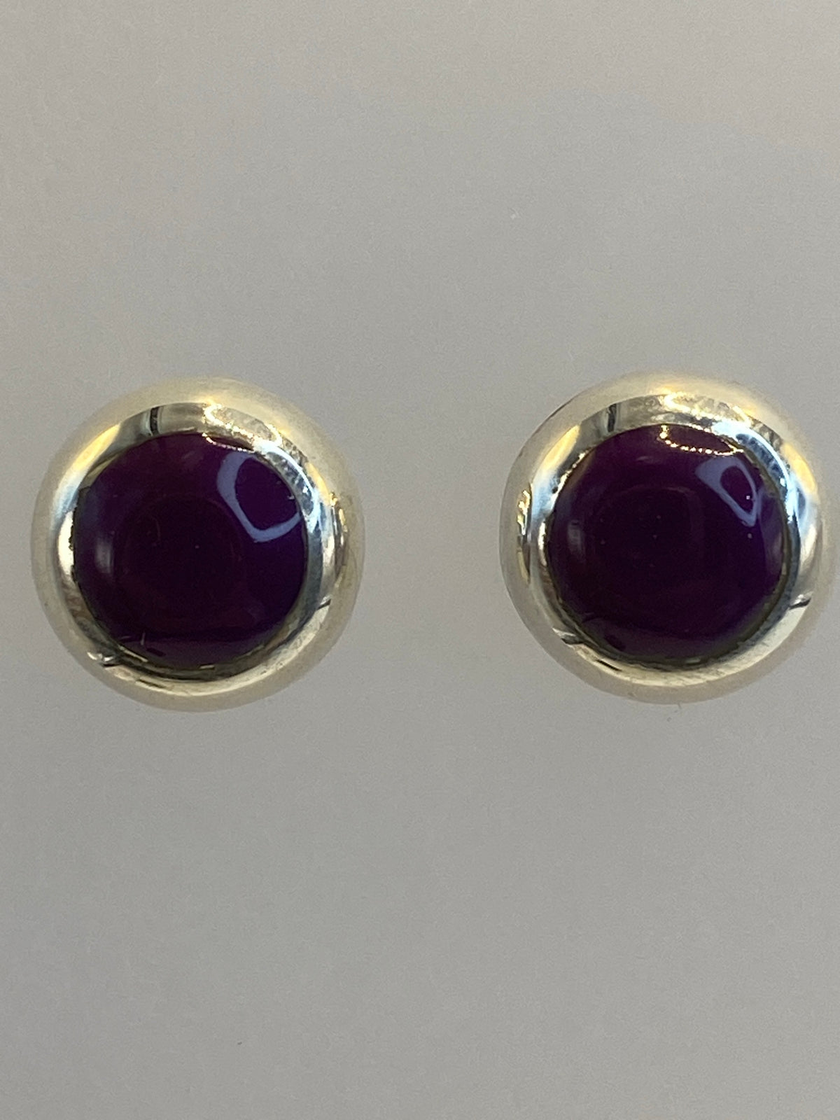 Aretes de plata delicados sobre escala de medidas, mostrando tamaño de 1 cm
