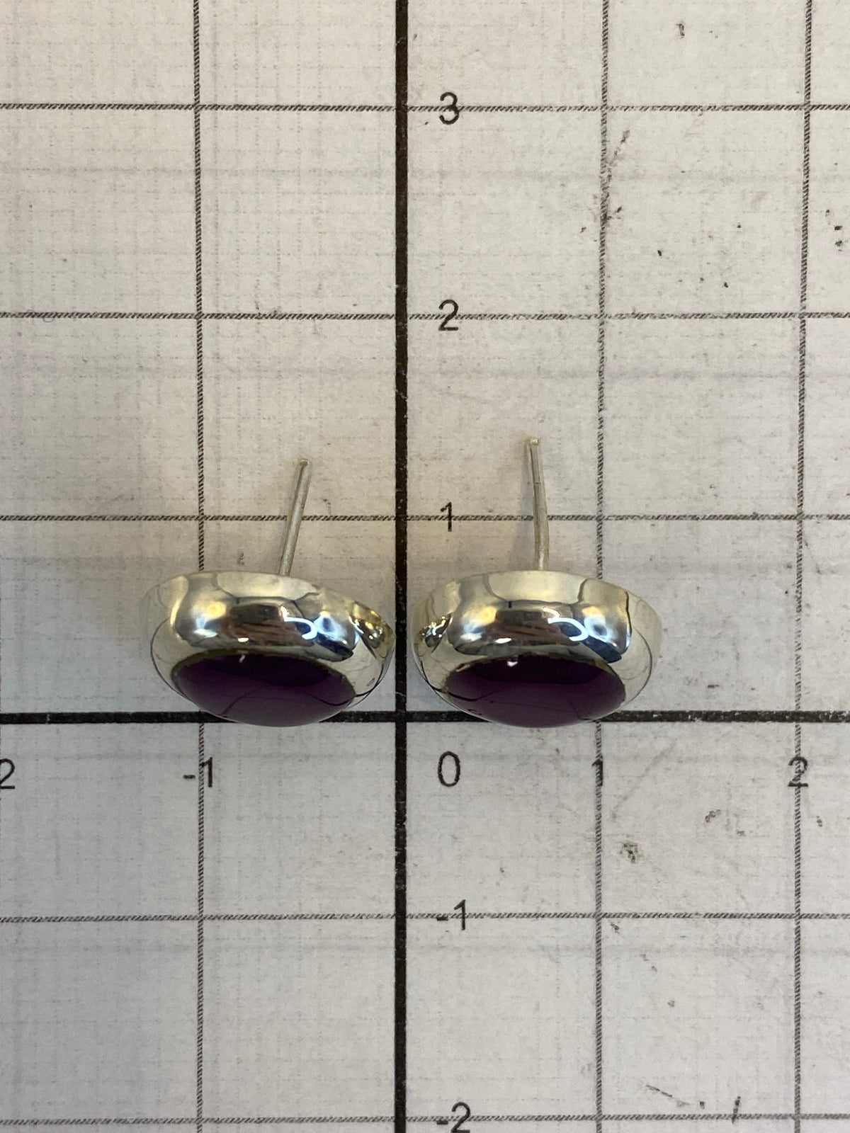 Par de aretes con piedra morada brillante en envase de joyería