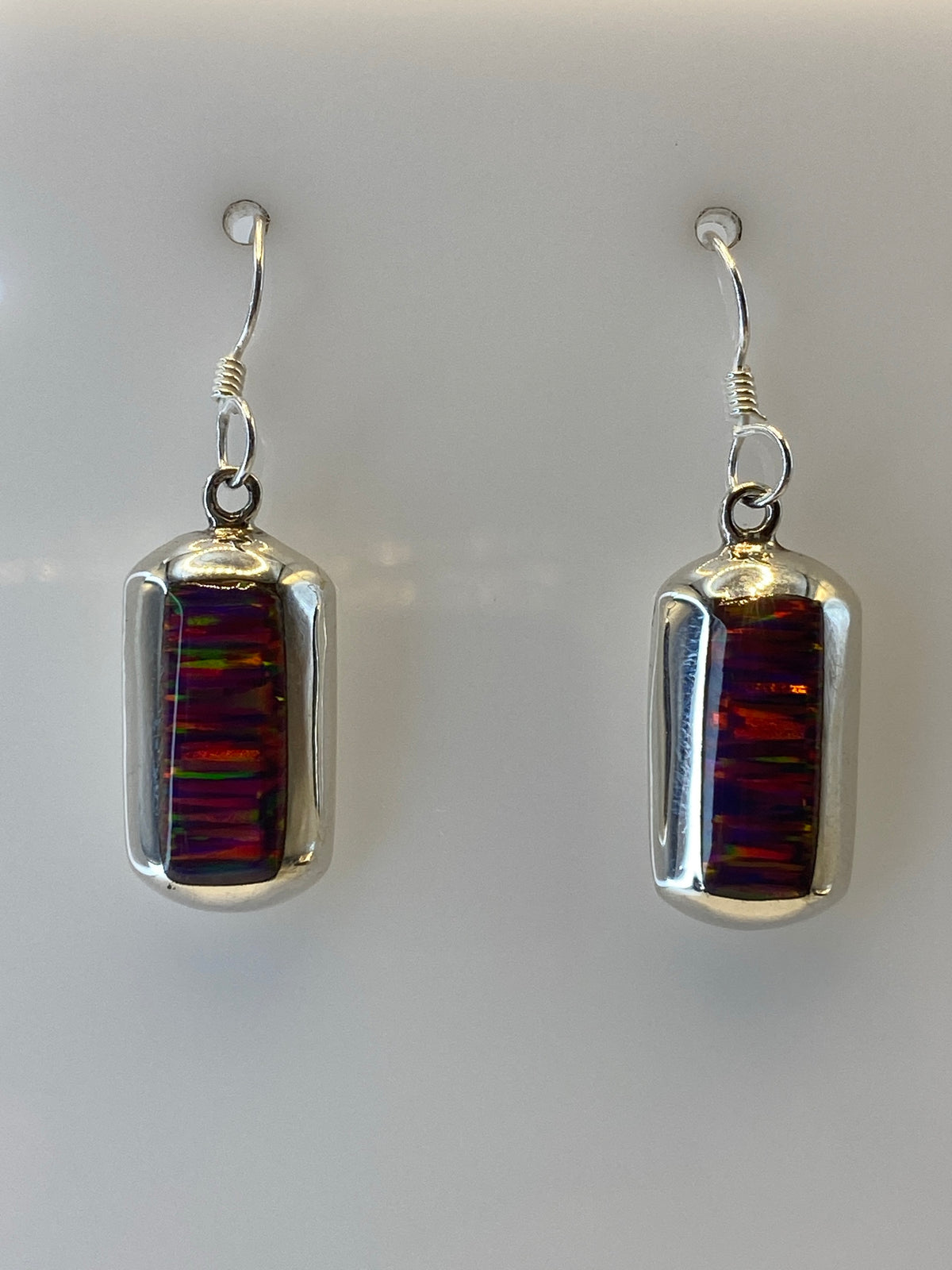 Arete individual mostrando el ópalo de fuego con vetas de rojo, naranja y amarillo en engaste de plata