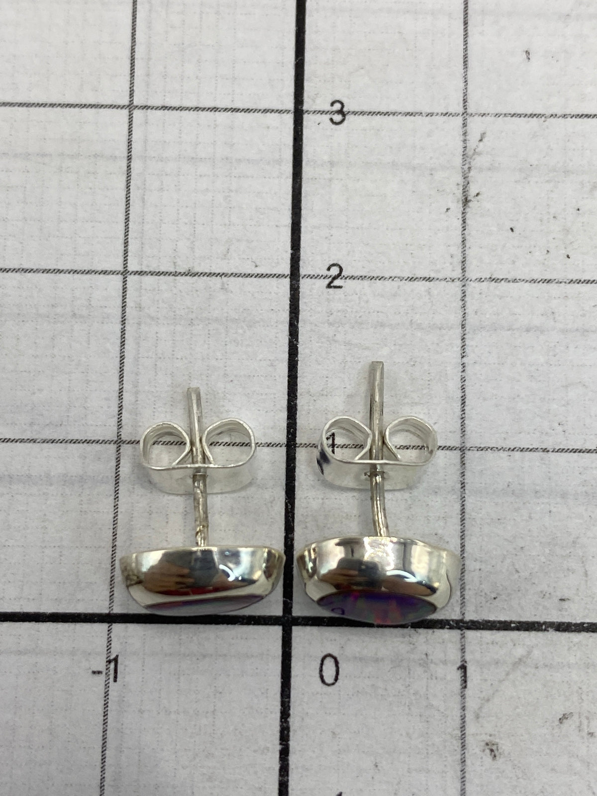Aretes de 1.3 cm en la mano mostrando el tamaño delicado y el brillo del ópal