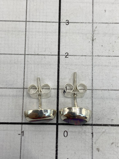 Aretes de 1.3 cm en la mano mostrando el tamaño delicado y el brillo del ópal