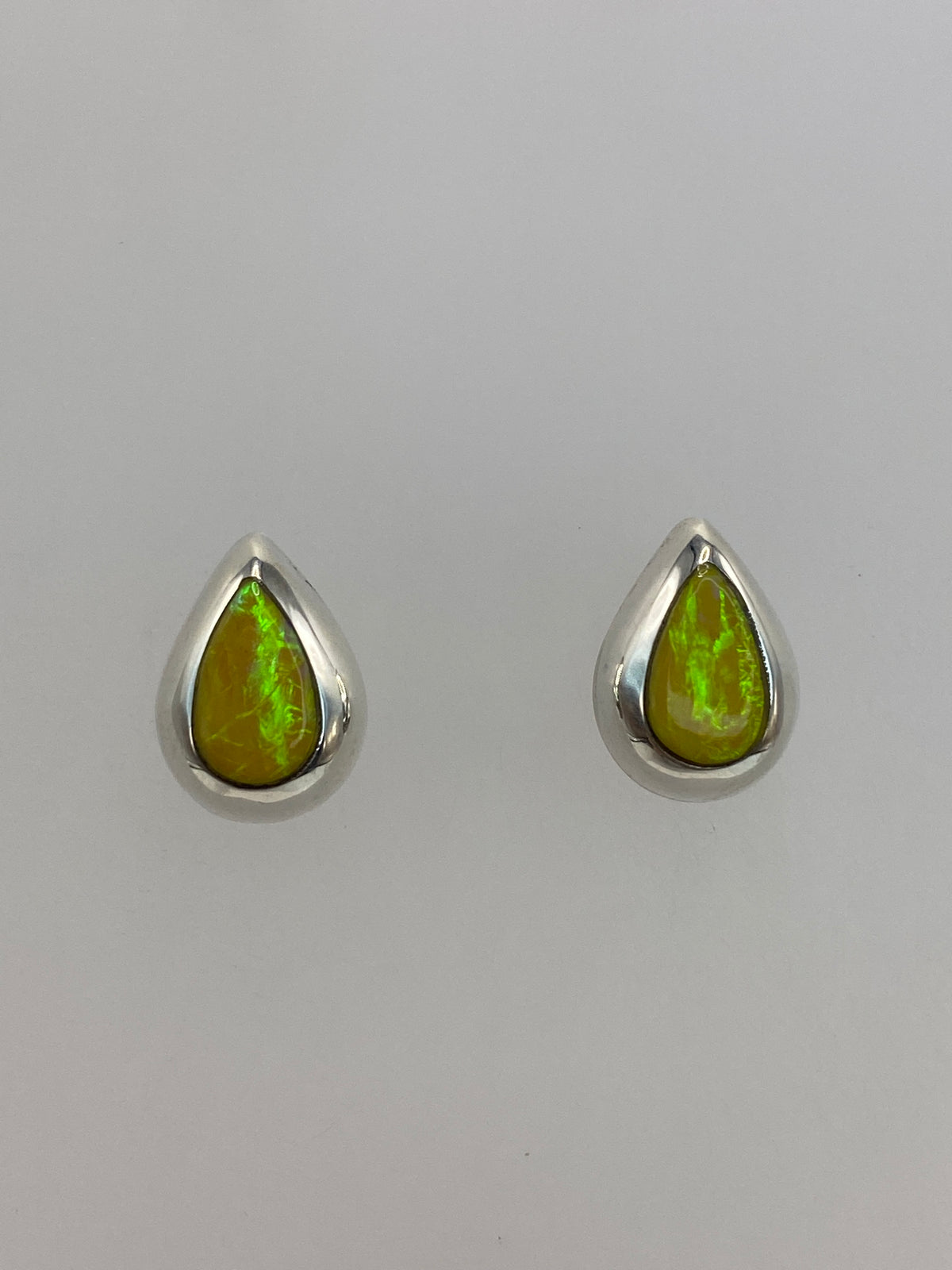 Aretes de plata con ópalo de fuego amarillo sobre fondo blanco