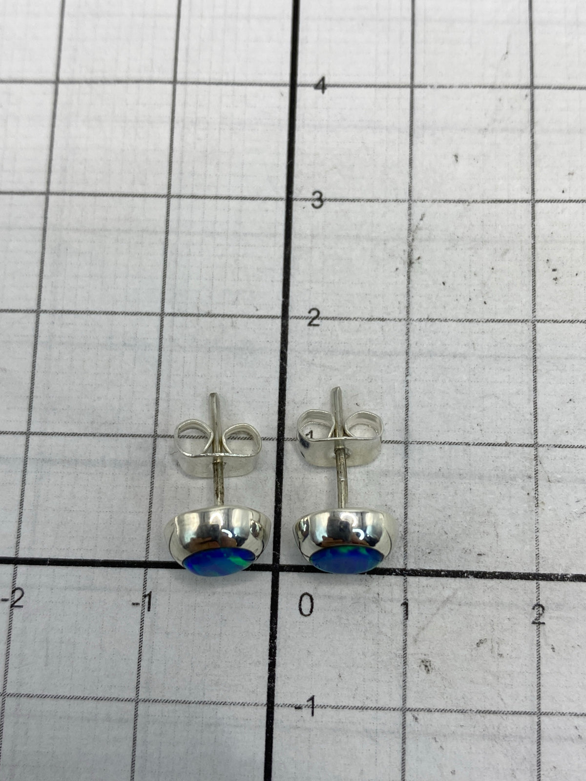 Aretes bajo luz natural destacando el destello azul del ópalo de fuego