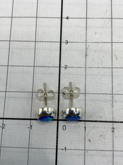 Aretes bajo luz natural destacando el destello azul del ópalo de fuego