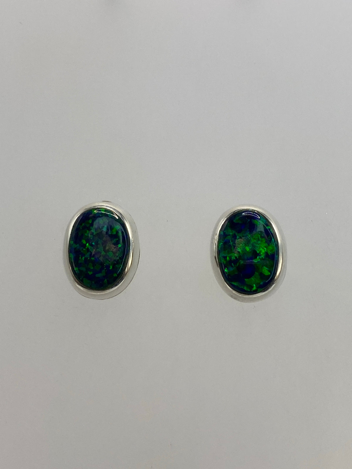Par de aretes de plata 925 con ópalo de fuego verde, vista frontal reflejando la luz