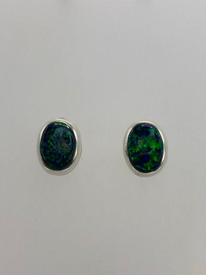 Par de aretes de plata 925 con ópalo de fuego verde, vista frontal reflejando la luz