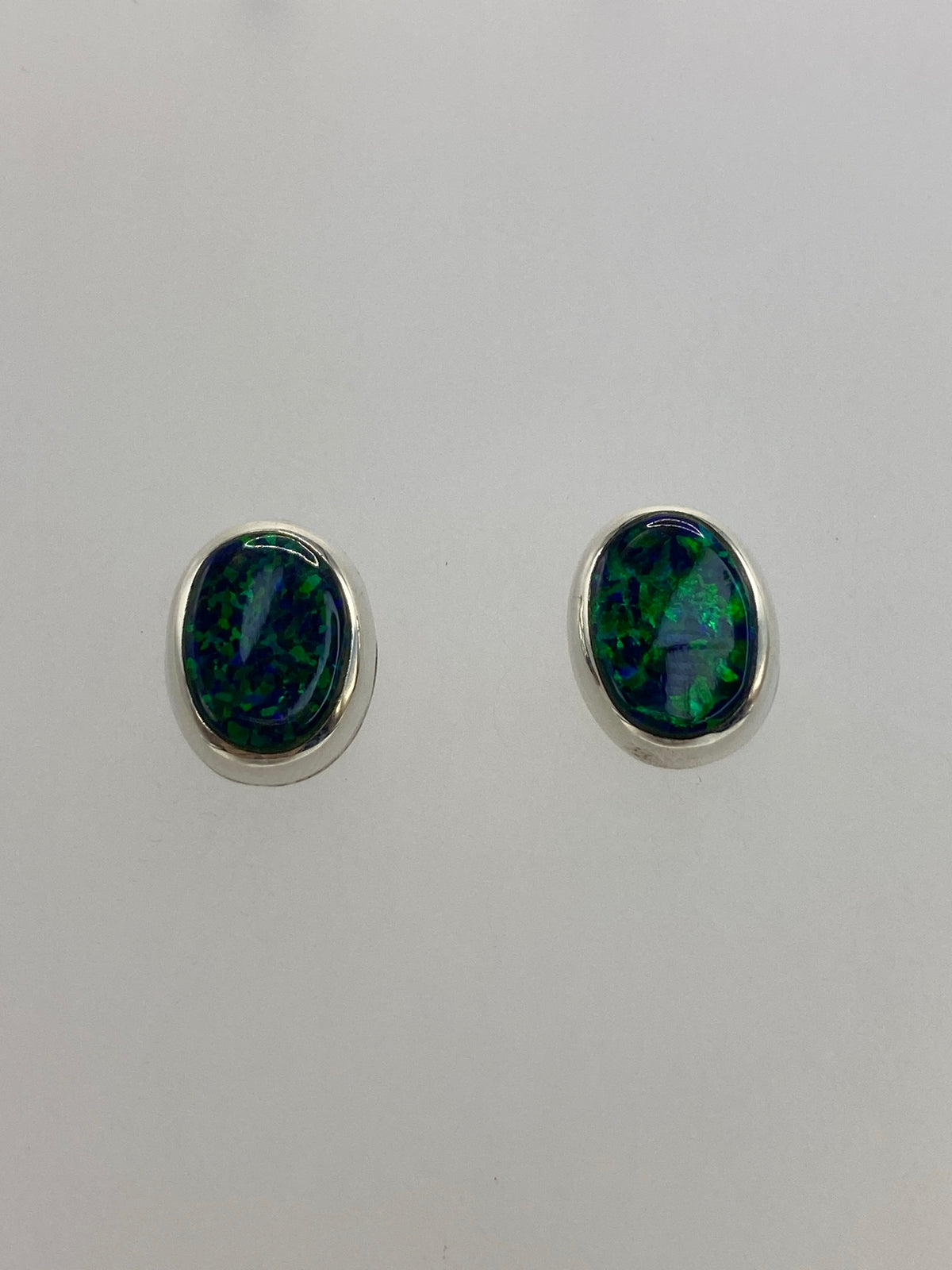 Aretes sobre fondo blanco mostrando el engaste de plata y la piedra verde