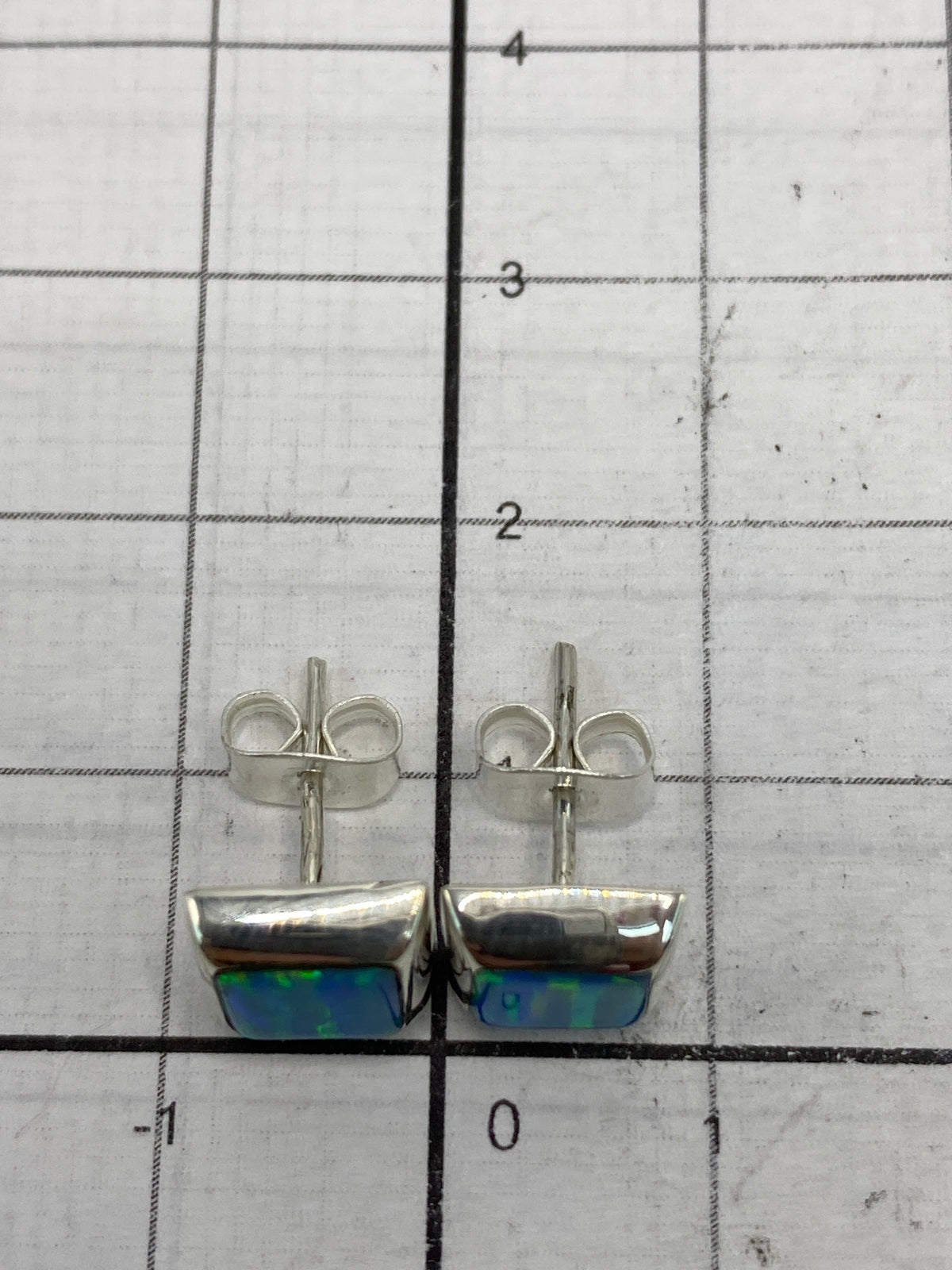 Aretes puestos en comparación de escala con centímetros, largo 1.3 cm