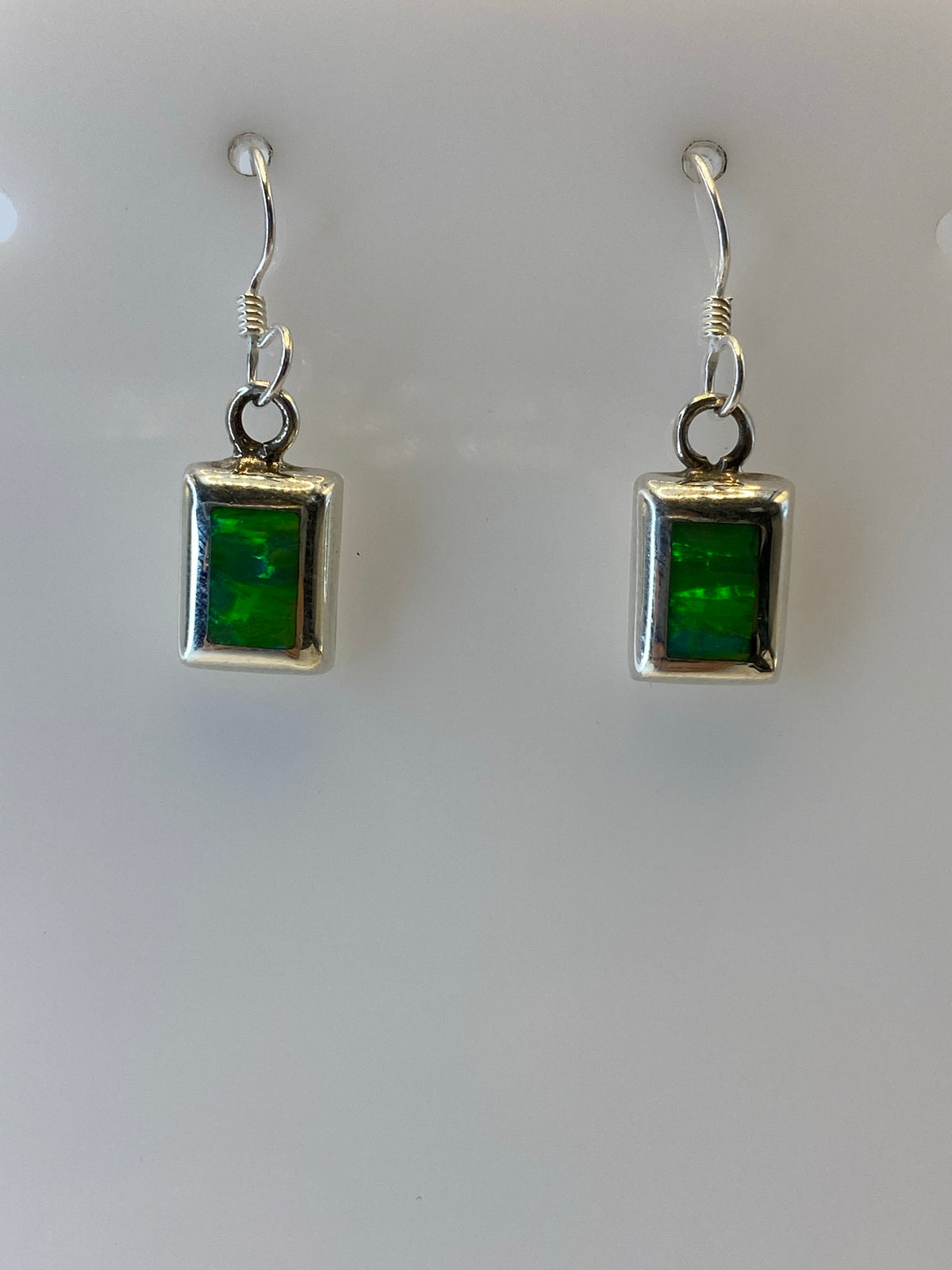 Detalle de la incrustación de piedra a mano en los aretes de ópalo de fuego