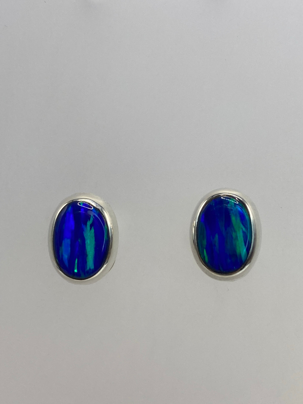 Par de aretes de plata 925 con ópalo de fuego azul, vistos desde el frente en detalle