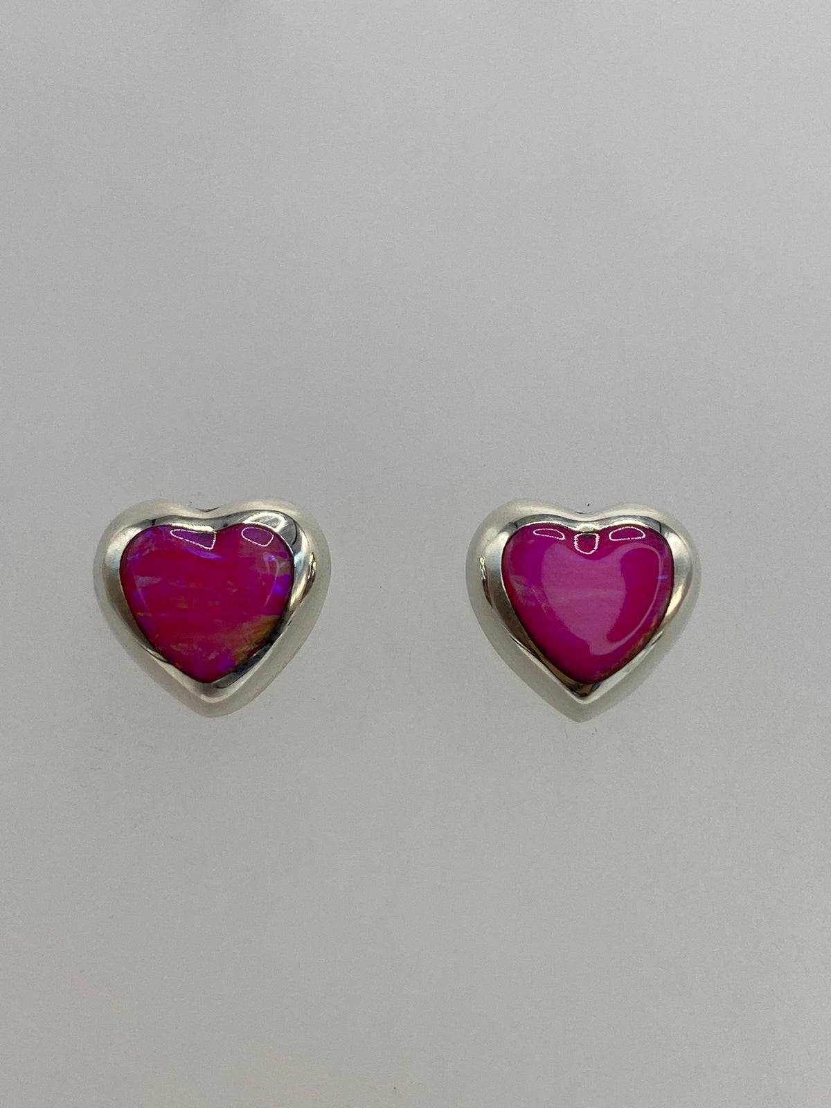 Par de aretes de plata con ópalo de fuego rosa brillante sobre fondo gris