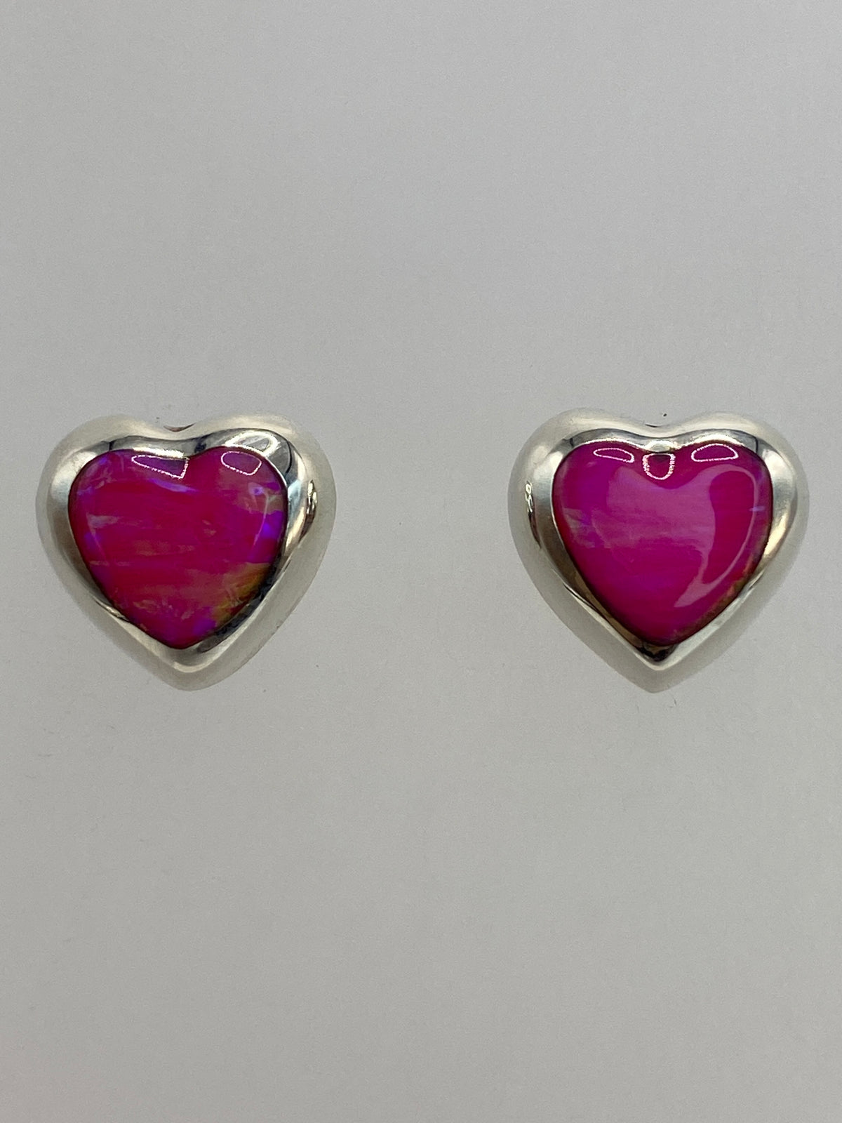 Aretes de plata con ópalo de fuego rosa sobre fondo blanco, vista de frente