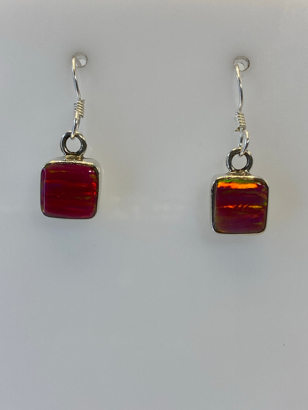 Par de aretes de plata con ópalo de fuego multicolor colgando del gancho