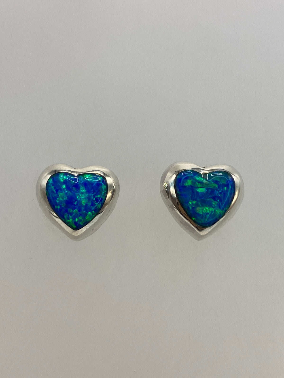 Par de aretes de plata con ópalo de fuego azul, engaste visible a mano