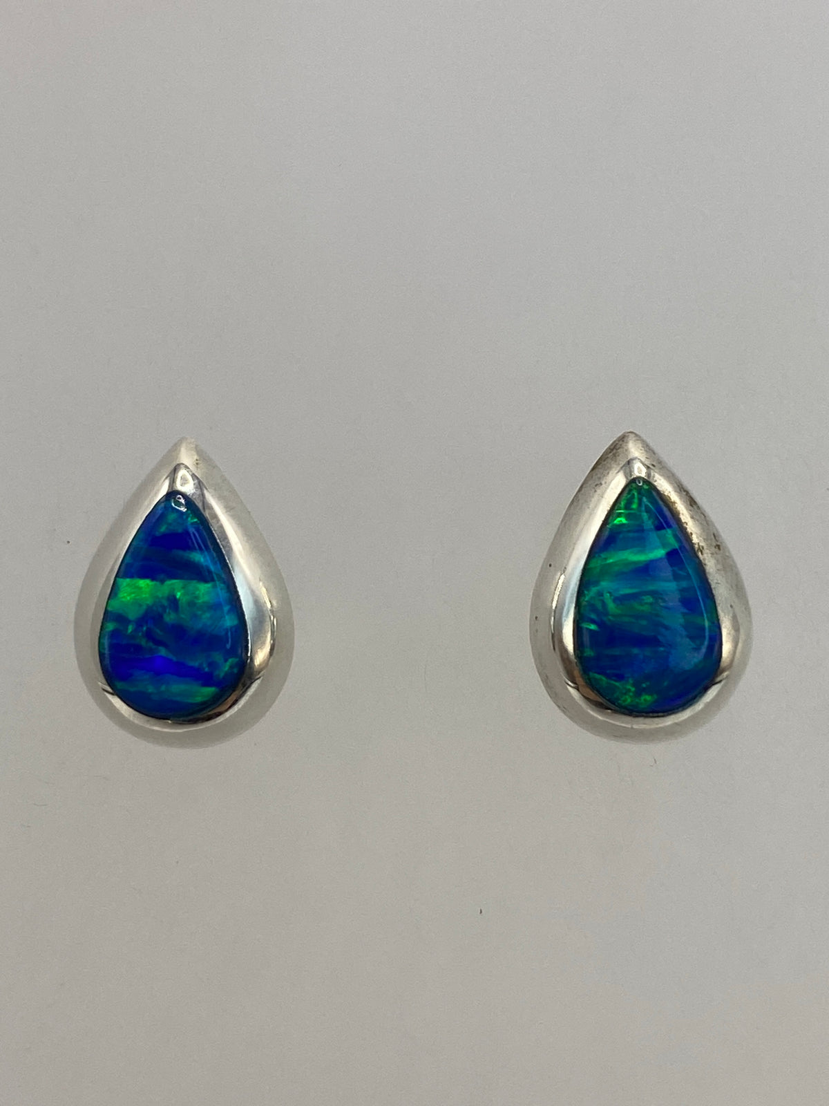 Aretes de plata con Ópalo de Fuego en la mano, mostrando el tamaño delicado de 1.3 cm