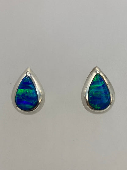 Aretes de plata con Ópalo de Fuego en la mano, mostrando el tamaño delicado de 1.3 cm