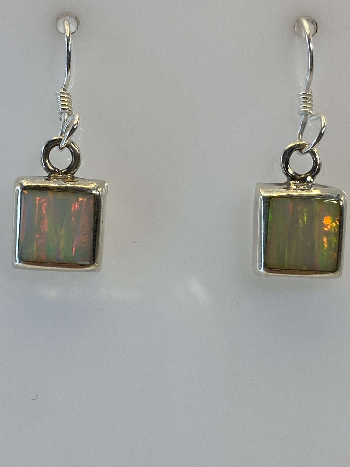 Detalle del ópalo de fuego en los aretes, viendo sus tonos multicolor