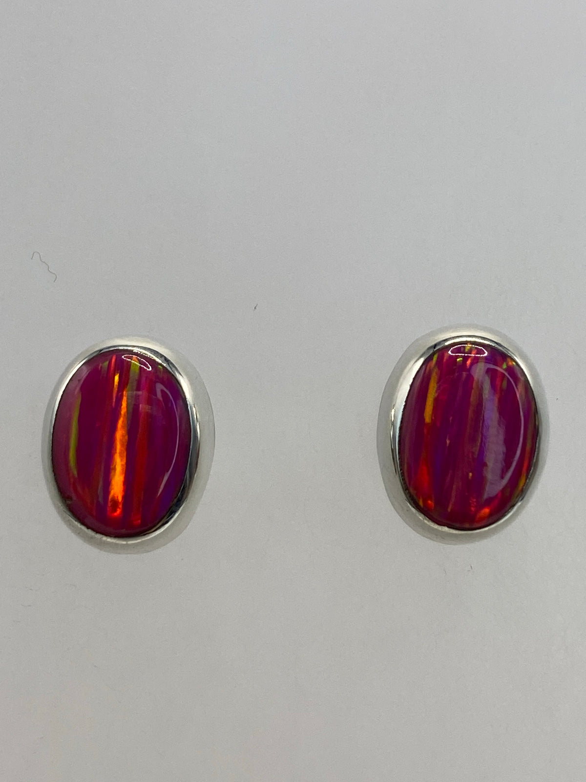 Aretes de Ópalo de Fuego mostrando el juego de luz rosa desde diferentes ángulos