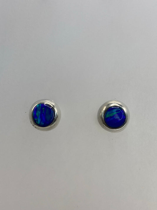 Par de aretes de plata con ópalo de fuego azul, vista frontal sobre fondo gris