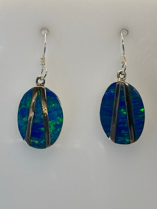 Aretes de plata con Ópalo de Fuego verde olivo colgando, mostrando los destellos de color
