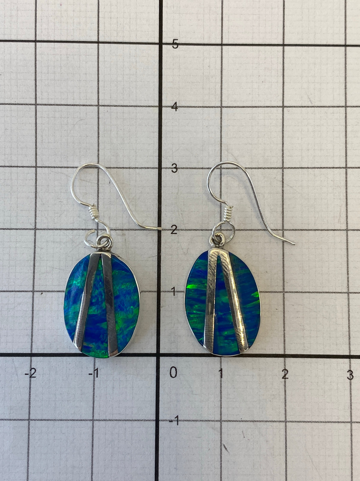Aretes sobre medidor de peso mostrando 2.3 gramos y Quinto 950