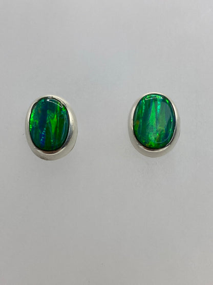 Vista frontal de los aretes de ópalo de fuego: piedra con efecto luminoso verde
