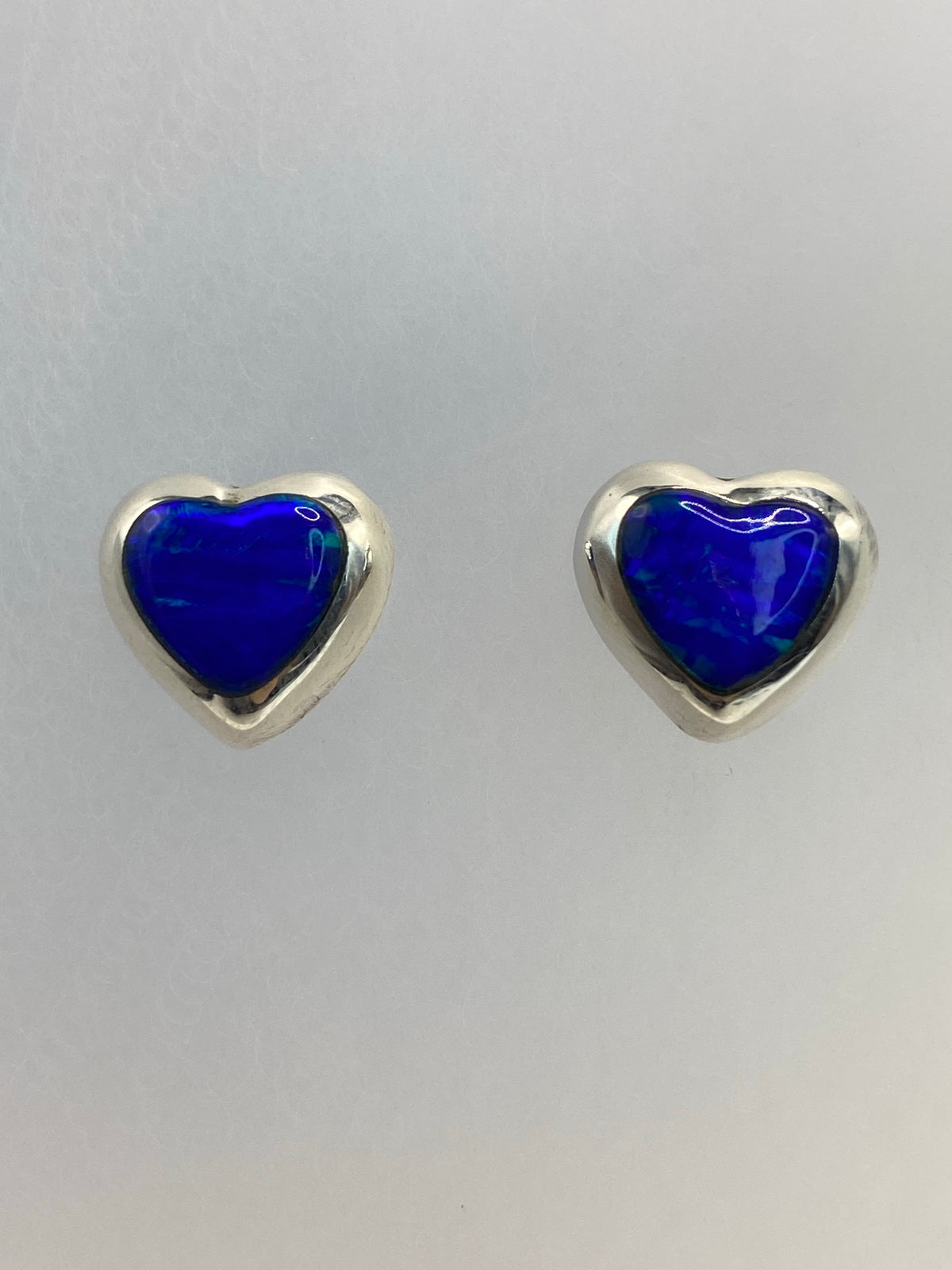 Aretes de plata con ópalo de fuego azul luminoso, vistos de frente