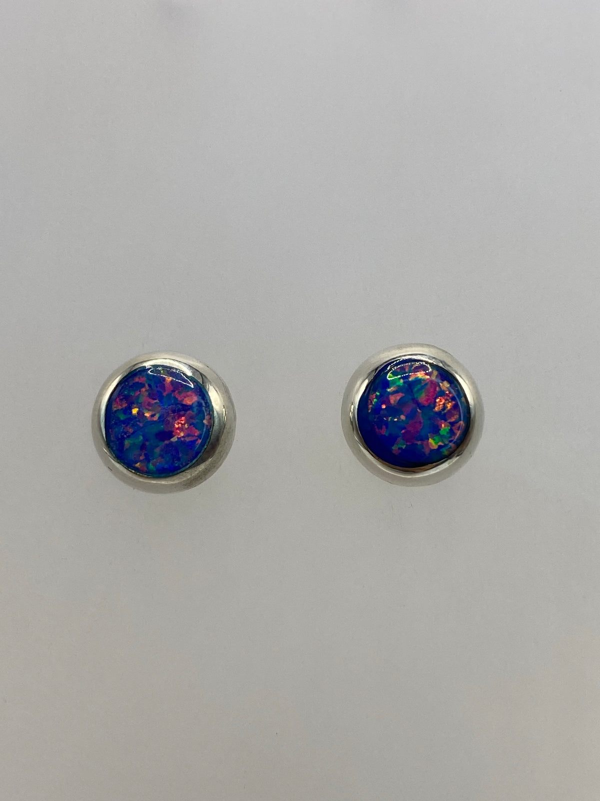 Par de aretes de plata 925 con ópalo de fuego multicolor, vista frontal mostrando el juego de colores naranja, verde y azul
