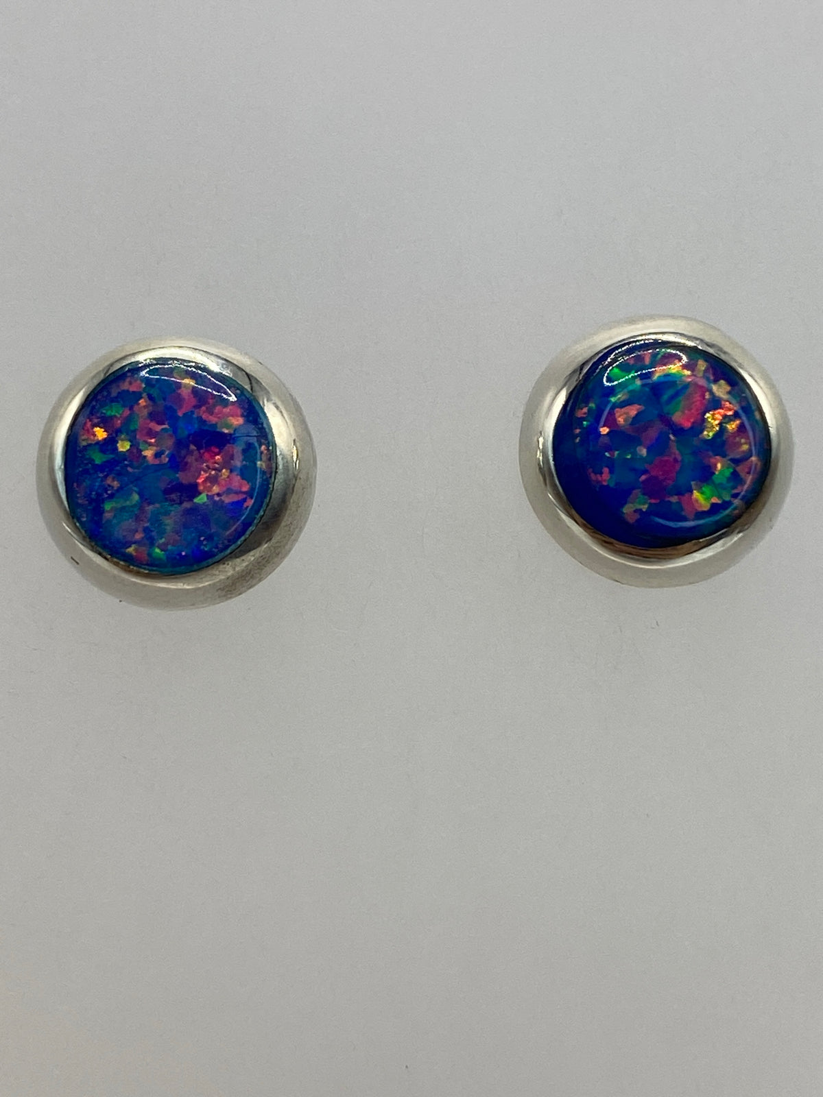 Aretes de plata ópalo de fuego en diferentes ángulos mostrando la iridiscencia