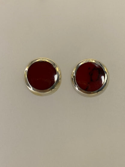 Detalle frontal de los aretes mostrando la piedra roja pulida y el engaste a mano