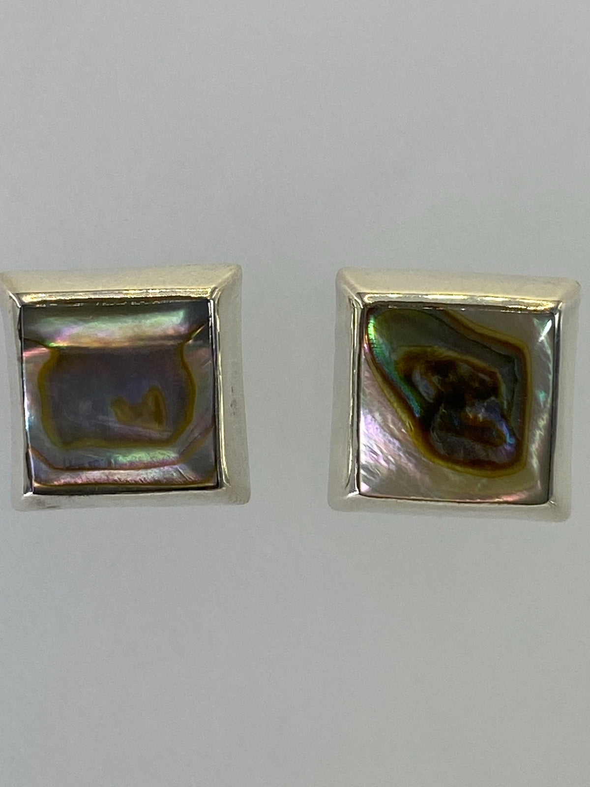 Vista frontal de los aretes de plata con piedra multicolor, diseño minimalista