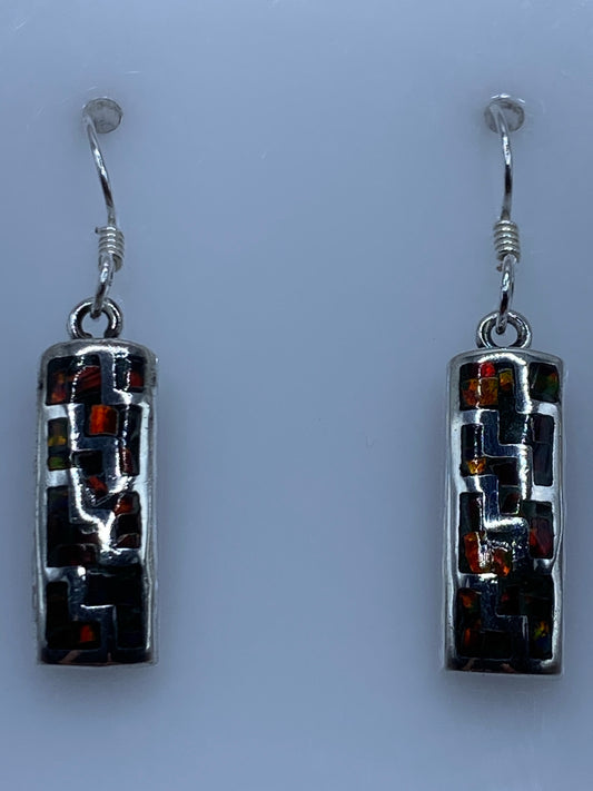 Par de aretes de plata con ópalo de fuego multicolor colgando sobre fondo gris claro