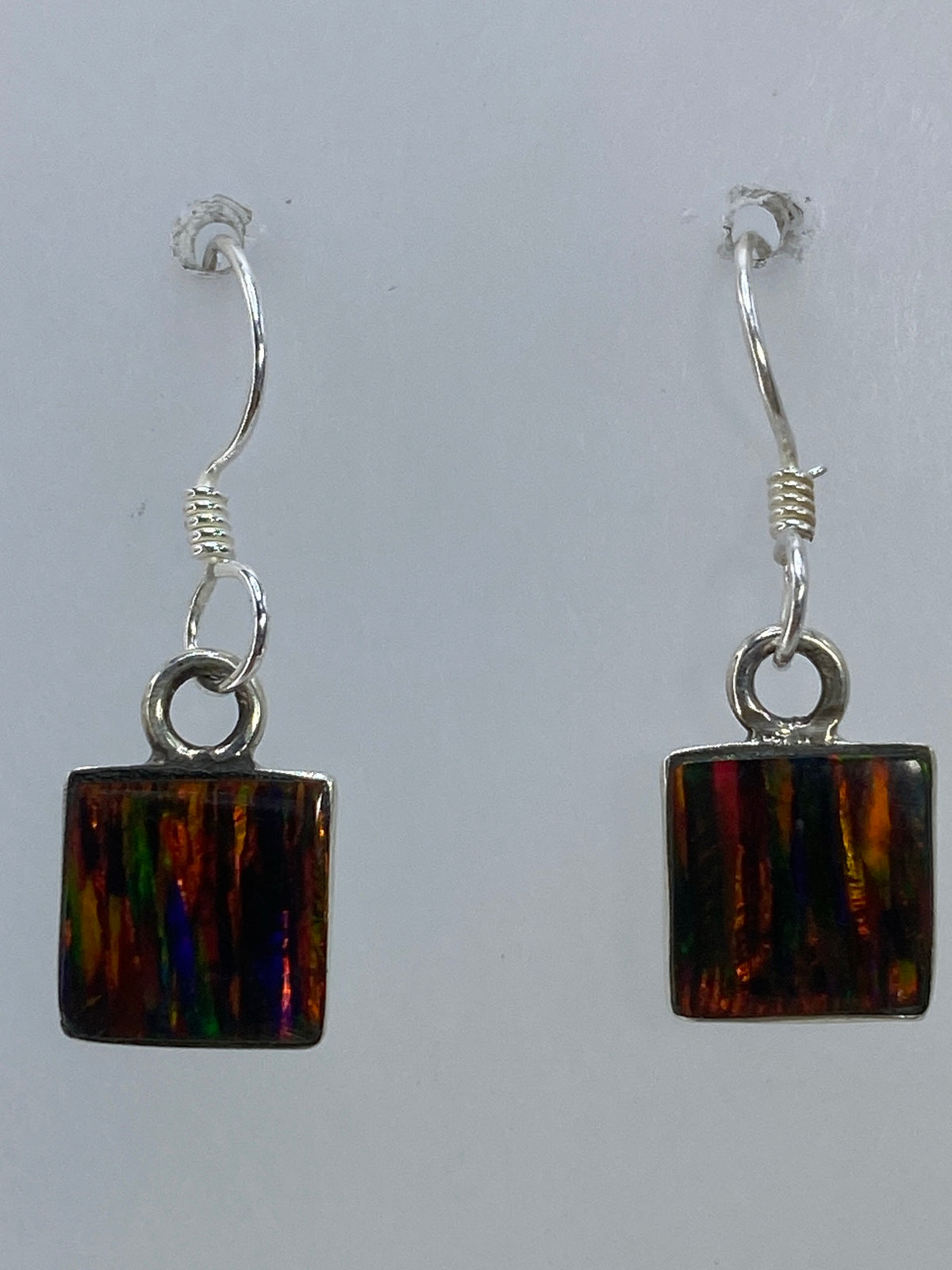 Ópalo de fuego multicolor en aretes de plata, con reflejos de luz roja, verde y azul