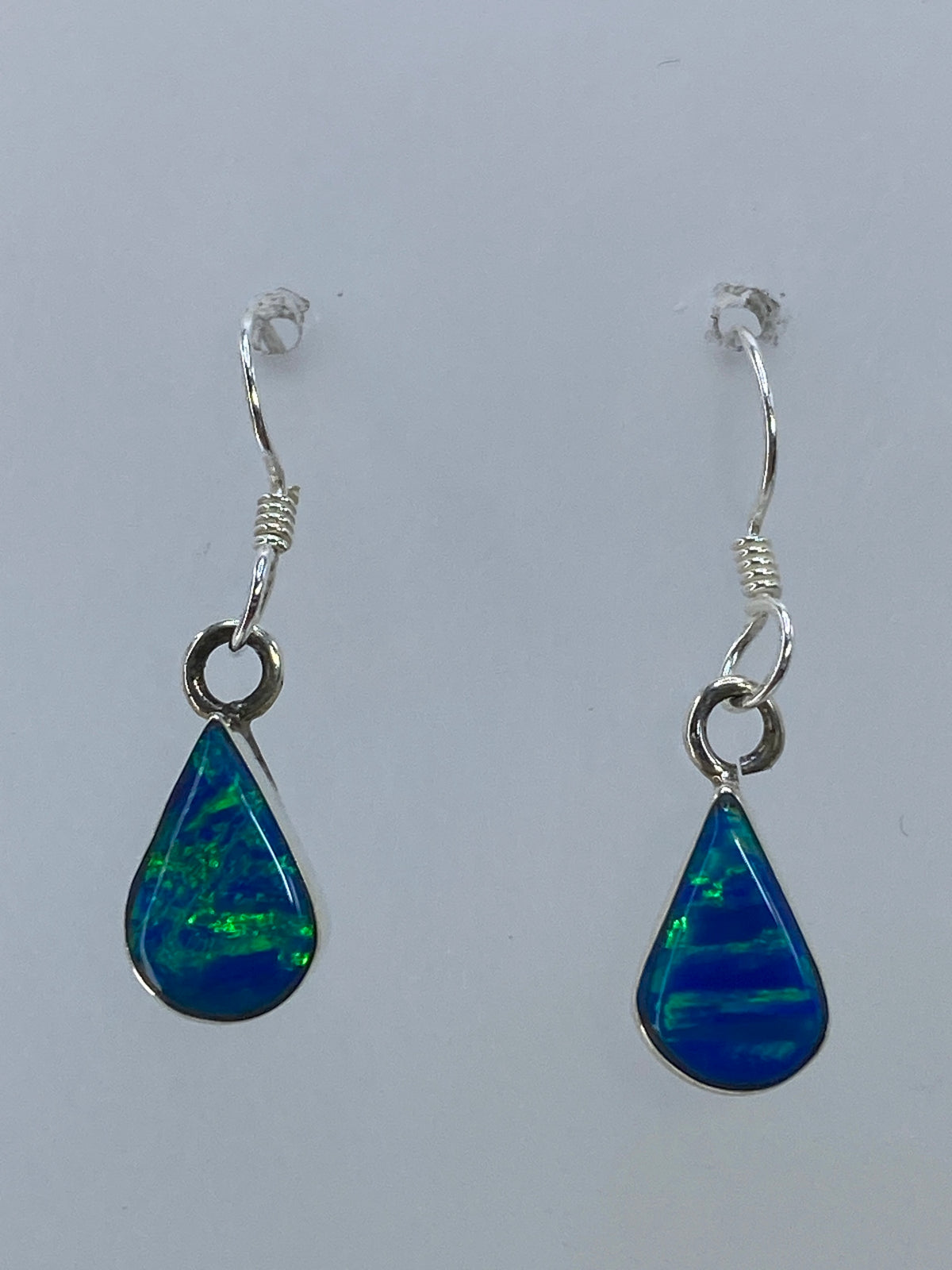 Par de aretes de plata con ópalo de fuego multicolor, luz verde y azul brillando