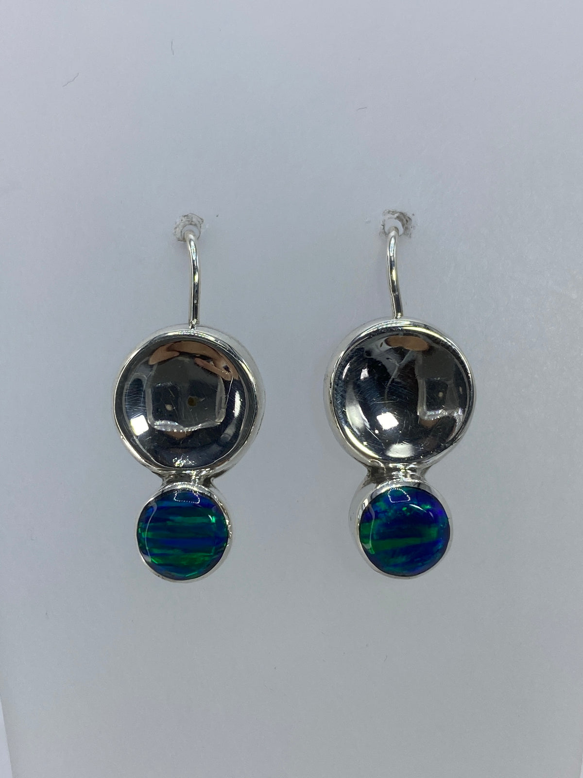 Detalle frontal de ambos aretes mostrando la incrustación de piedra y el brillo del ópalo verde