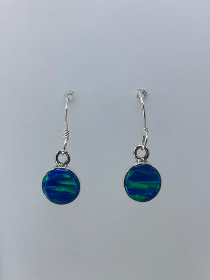 Aretes de ópalo de fuego mostrando juegos de luz verde, azul y naranja en el engaste