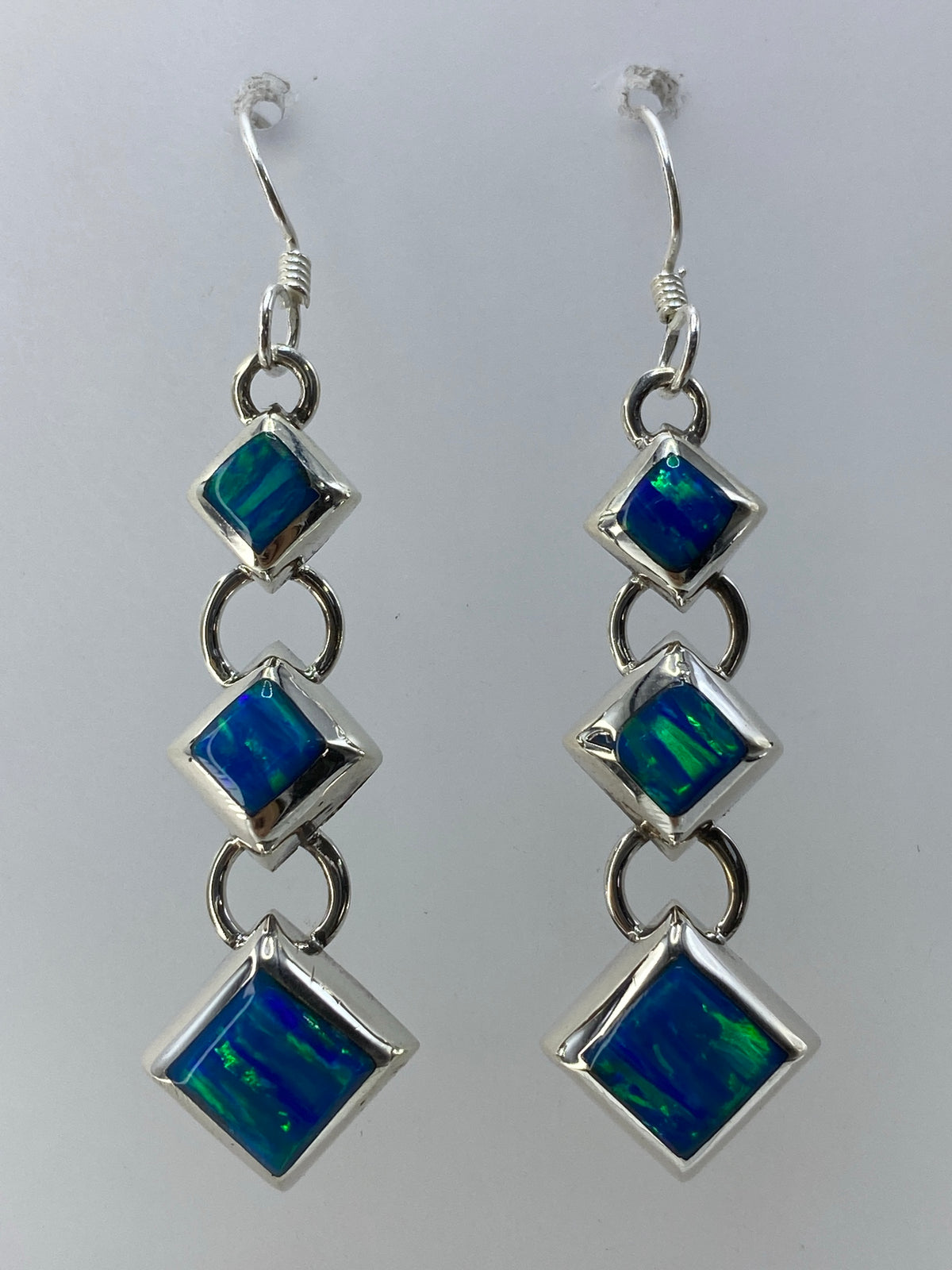 Par de aretes de plata 925 con ópalo de fuego verde limón en cascada, colgando ante fondo blanco