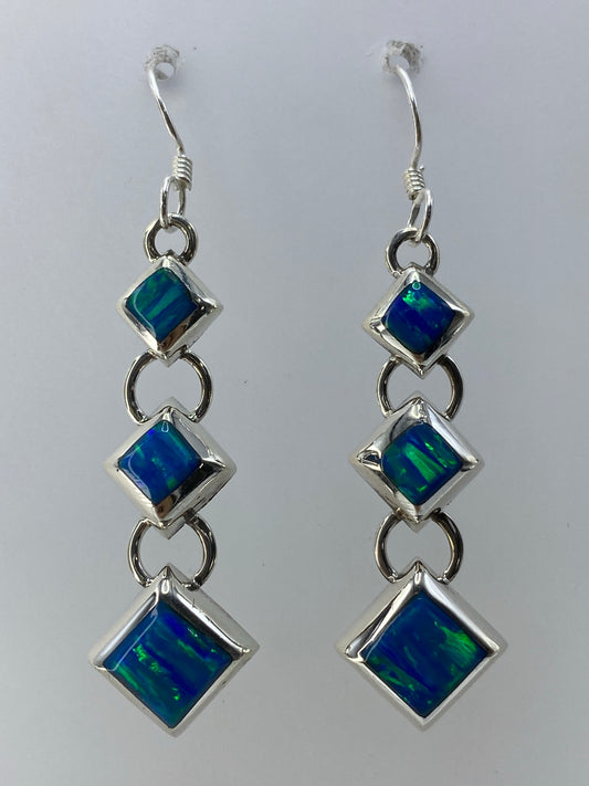 Par de aretes de plata 925 con ópalo de fuego verde limón en cascada, colgando ante fondo blanco