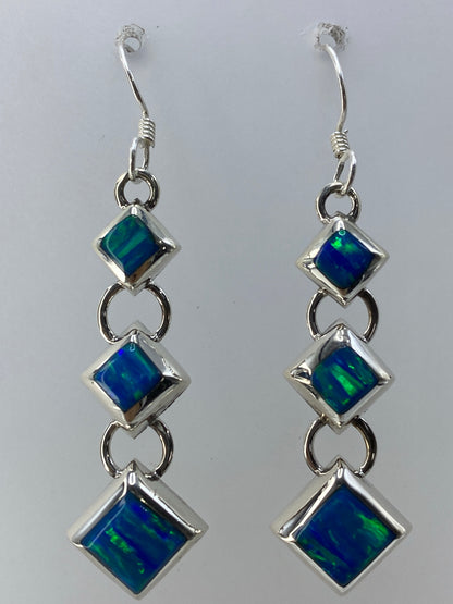 Aretes en la mano mostrando el tamaño real de 4.5 cm y el brillo verde del ópalo