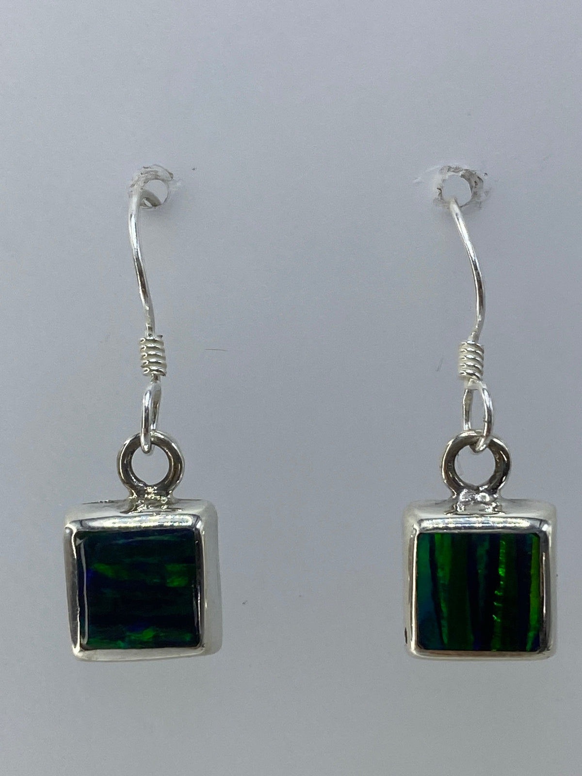 Aretes puestos en oreja de mujer, mostrando el brillo del ópalo