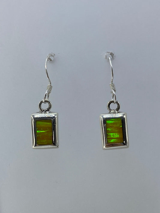 Detalle del engaste a mano del ópalo de fuego en plata, mostrando los colores iridiscentes verde y naranja
