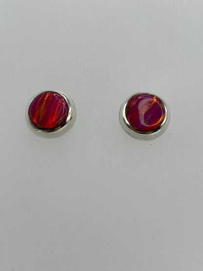 Aretes ópalo de fuego mostrando la iridiscencia rosa bajo luz natural
